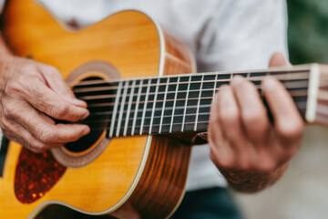 Obraz premium A close-up of hands strumming an acoustic guitar, showcasing the instrument's wood and strings, evoking a sense of music and craftsmanship.