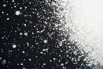 Obraz premium A black and white photo of snowflakes falling on a dark background