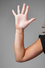 A raised hand demonstrating a gesture of greeting with a neutral background