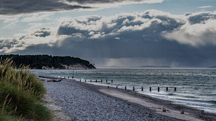 Fototapeta premium Strand bei Findhorn mit dramatischer Wolkenstimmung, Regen im Hintergrund, Dünengras im Vordergrund