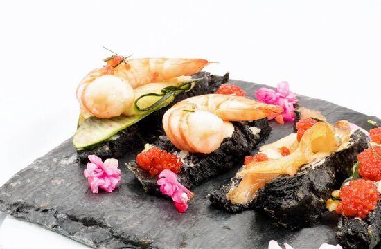 Tartine produits de la mer avec crevette, caviar, &oelig;ufs de lump et saumon sur pain noir au charbon, assiette en ardoise tournant en plan fixe, d&eacute;cor floral