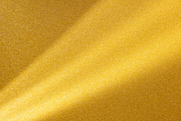 Clean paper background, light beams raking across glittery gold sandy coloured textured sparkling paper. Copy space.