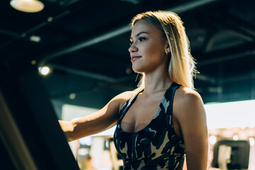 Cheerful woman exercising on running track in gym