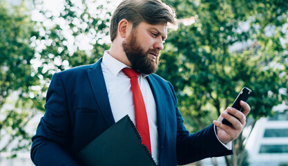 Stressed businessman reading message using smartphone