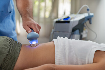 Physical therapist uses ultrasound therapy on a patients lower back to relieve pain and promote...