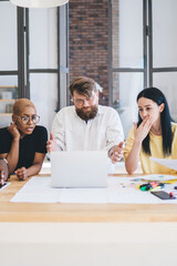 Fototapeta premium Group of shocked multiethnic coworkers using laptop at office