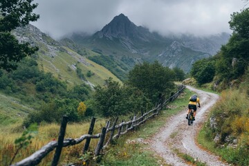Fototapeta premium Cyclist riding mountain bike on gravel road in italian alps