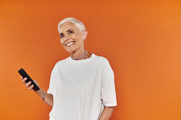 A confident woman with short hair enjoys a moment holding her phone.