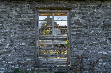 Blick durch das Fenster eines verfallenen Hauses im Norden Schottlands, im Inneren und am Dach w&auml;chst Gras