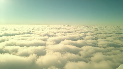 Obraz premium Airplane wing in flight above an endless cloud layer with a blue sky overhead, capturing the beauty and tranquility of midair travel