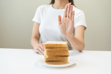 Gluten allergy, asian young woman hand push out, refusing to eat white bread slice on plate in...