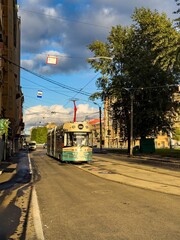 Obraz premium A vintage-inspired tram travels down a quiet street in Saint Petersburg, illuminated by the warm afternoon sunlight. The tram retro design harmonizes with the historic architecture of the city