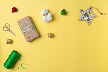 Fototapeta na wymiar Christmas yellow background with gift boxes, scissors, string and decorations. Gift wrapping concept. Flat lay, top view. Copy space