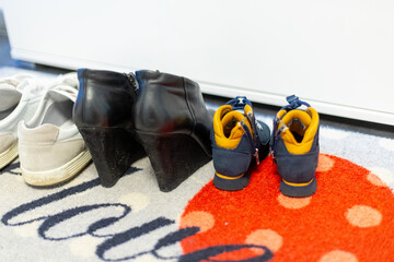 Family shoes at home at the entrance, woman heels, man sneakers and kids shoe
