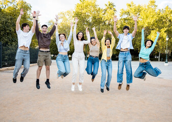 A group of 8 young people of different ethnicities between 18 and 25 years old have fun in the street at sunset.Millennials are jumping in a park at the same time.Concept of youth groups.