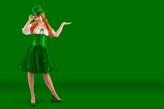 Young red-haired woman in a green Leprechaun elf costume during a St. Patrick's Day party. Happy Irish girl showing thumb up. Ireland National Independence Day March 17th