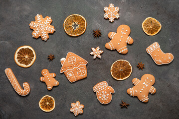 Christmas set of gingerbread cookies and dried orange slices on dark background, top view, flat lay