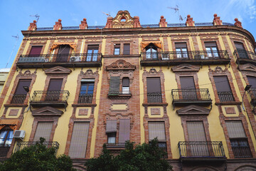Obraz premium Colorful facade of residential buildings with extremely small balconies behind wrought iron railings. Seville, Andalusia, Spain, Europe.