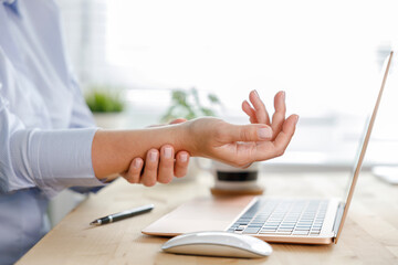 Young woman with wrist pain while using laptop