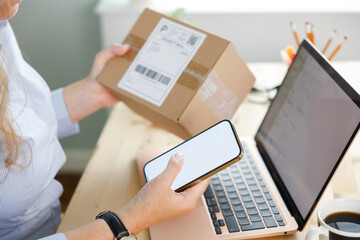Young woman holding cardboard box, checking her online order