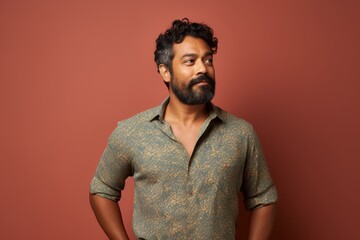 Fototapeta premium Portrait of a satisfied indian man in his 30s donning a trendy cropped top while standing against solid color backdrop