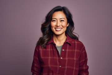Fototapeta premium Portrait of a content asian woman in her 40s wearing a comfy flannel shirt in front of solid color backdrop