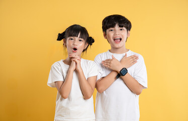Portrait of Asian kid girl and kid boy  posing on yellow background