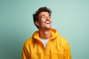 Fototapeta premium Portrait of a joyful man in his 20s wearing a lightweight packable anorak isolated on solid color backdrop