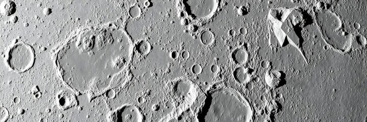 Craters and valleys create a rugged, pockmarked texture on the surface of the moon, rocky, desolate