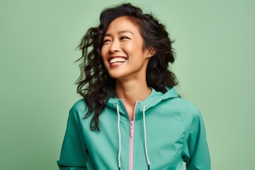 Fototapeta premium Portrait of a joyful asian woman in her 30s sporting a breathable hiking shirt on solid pastel color wall