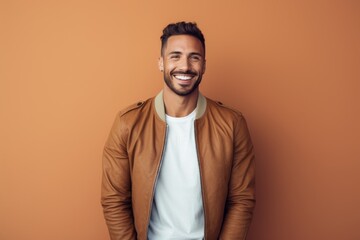 Fototapeta premium Portrait of a smiling man in his 30s wearing a trendy bomber jacket over solid pastel color wall
