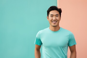 Fototapeta premium Portrait of a content asian man in his 30s wearing a moisture-wicking running shirt in front of solid pastel color wall