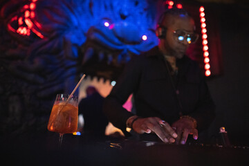 DJ plays music on a controller at a party and close up alcoholic cocktail