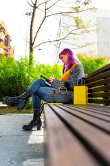 Body positive autistic girl with pink hair drawing on a tablet sitting in a park