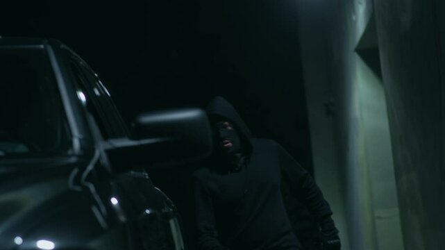 Two unrecognizable criminals getting in car while being pursued by police after committing crime at night