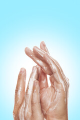 Hands applying moisturizing lotion on blue background.