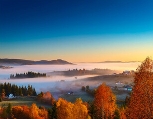 Fototapeta premium Landscape with fog in the valley and an autumn village