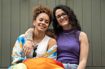 Front view of happy lesbian young couple hugging while sitting in front of the camera isolated on green background