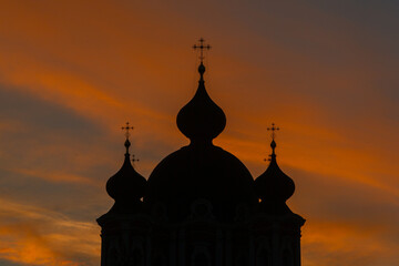 Silhouette of an Orthodox church against the background of the setting sun.