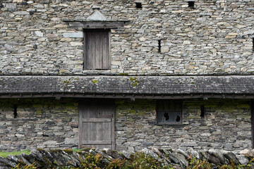 The side of an old stone barn with closed doors and windows in Keswick in the Lake District