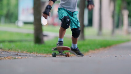 Close-up of a young boy skateboarding, legs in motion as he pushes off the ground. wearing knee...
