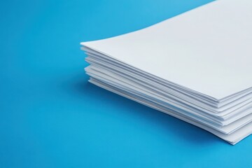 A neatly aligned stack of unfinished paperwork rests on a clean blue surface, showcasing an organized workspace that highlights pending tasks and meticulous arrangement.