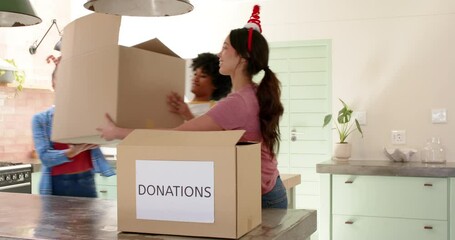Christmas time, Women friends wearing festive headbands packing donation boxes in cheerful kitchen