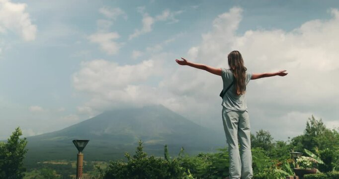 Woman gazes at mayon volcano, its cone shape against the sky, inviting exploration in the lush philippines landscape. Feel wanderlust and thrill in this famous landmark