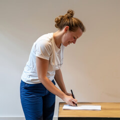 Fototapeta premium A woman writes something on a piece of paper on the table 
