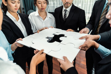 Multiethnic business people holding jigsaw pieces and merge them together as effective solution...
