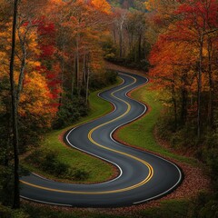 Fototapeta premium Winding road through vibrant autumn foliage in mountainous region