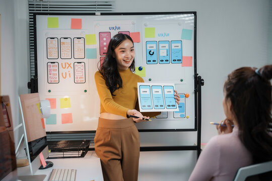 Asian women working together developing user interface of mobile application using wireframe and sticky notes