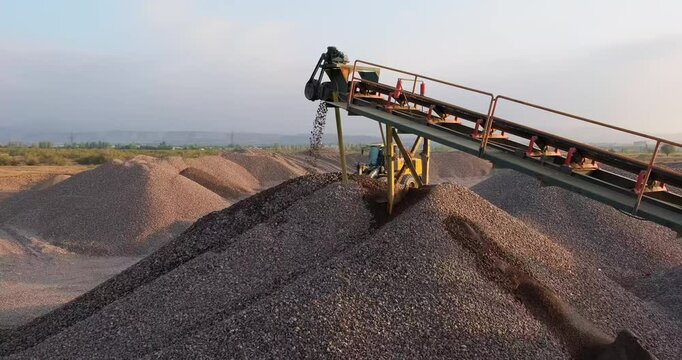 Sorted rocks moving on conveyor line, falling in a pile. Mining conveyor belt sorting rocks. Crushing screening plant. Gravel extraction