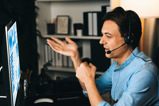 Call center consulting with customers on headphones on monitor in business paragraph with typing on pc with dynamic data marketing analysis planning at modern home office at night time. Pecuniary.